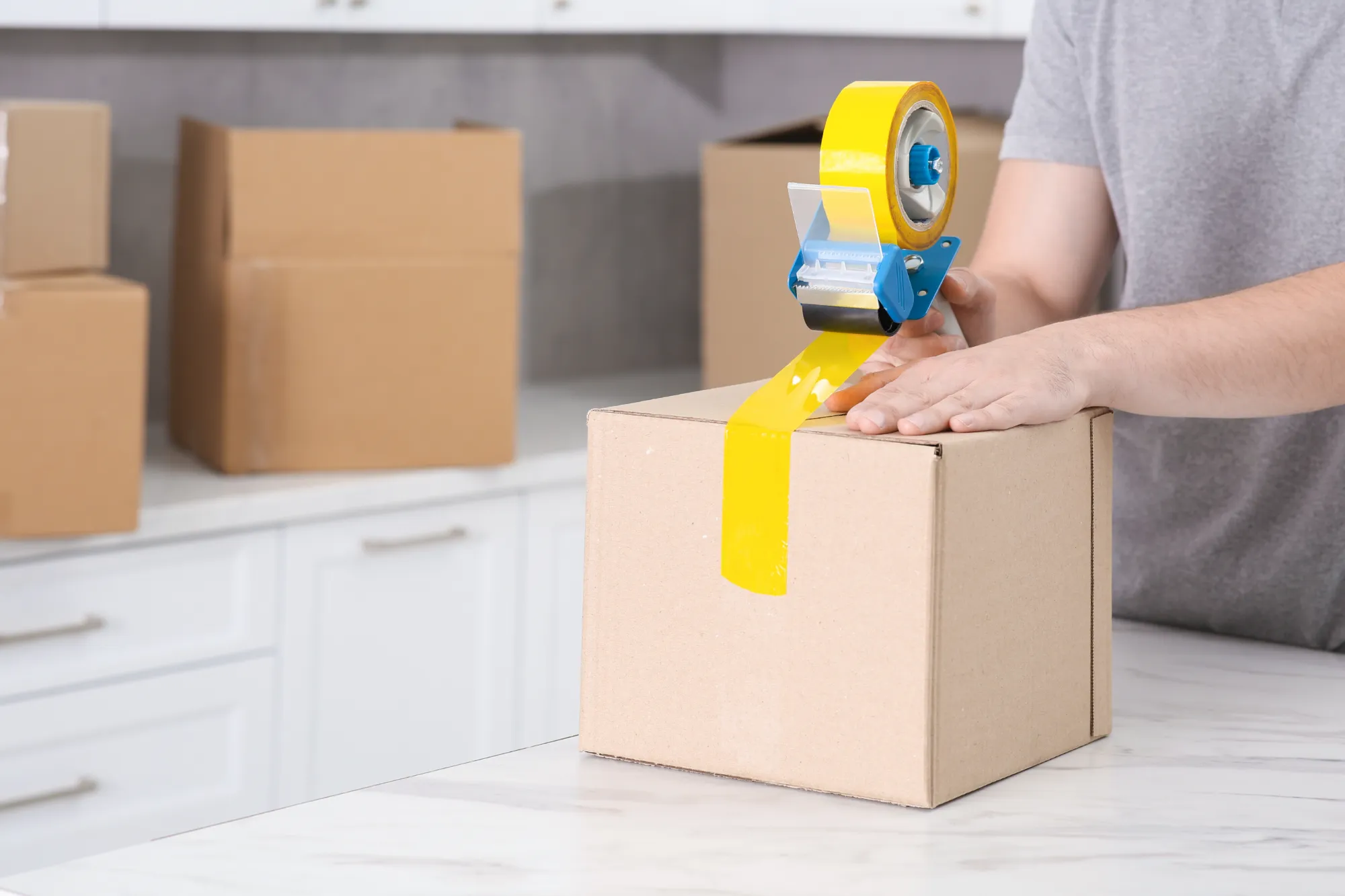 Hand using a tape dispenser to seal a cardboard box